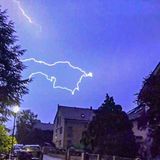 Ein Blitz ist am dunkelblauen Himmel über Häusern zu sehen