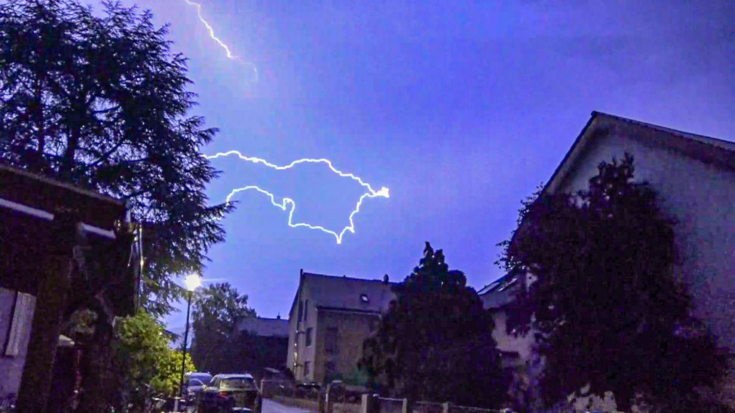 Ein Blitz ist am dunkelblauen Himmel über Häusern zu sehen