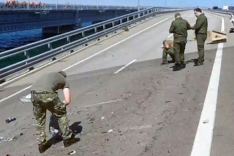 Auf einer zweispurigen Fahrbahn der Kertsch-Brücke zwischen Russland und der Krim sind vier Menschen in Uniformen beschäftigt
