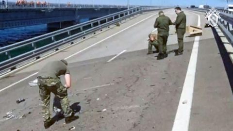 Auf einer zweispurigen Fahrbahn der Kertsch-Brücke zwischen Russland und der Krim sind vier Menschen in Uniformen beschäftigt