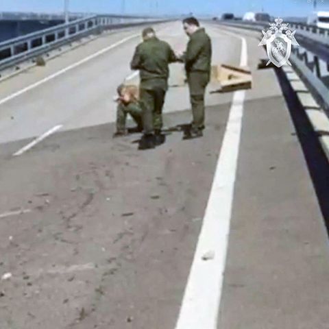 Auf einer zweispurigen Fahrbahn der Kertsch-Brücke zwischen Russland und der Krim sind vier Menschen in Uniformen beschäftigt