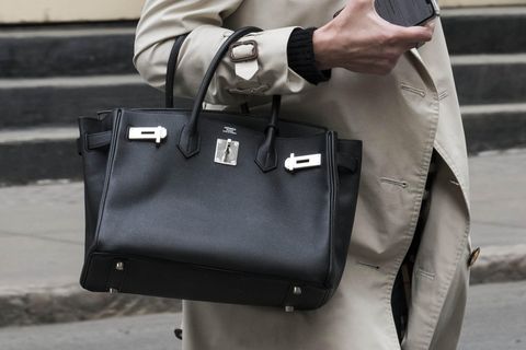 Eine Frau mit einer schwarzen Birkin Bag am Arm