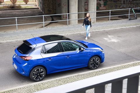 Ein Auto steht vor einem Parkhaus. Eine Frau geht darauf zu