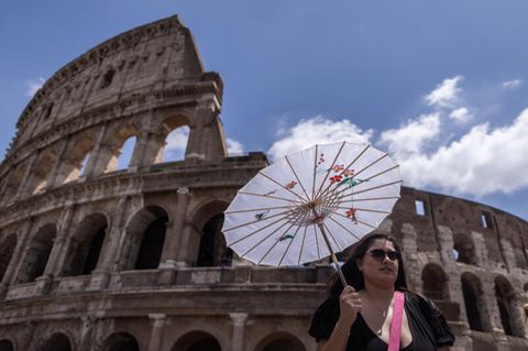 Eine Touristin mit Sonnenschirm vor dem Kolosseum