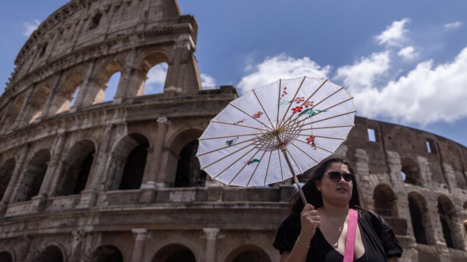 Eine Touristin mit Sonnenschirm vor dem Kolosseum