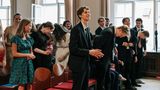 Die Abiturienten stehen schick angezogen vor aufgereihten Stühlen