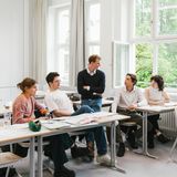 Fünf Schüler:innen sitzen zusammen beim Lernen in einem Klassenzimmer