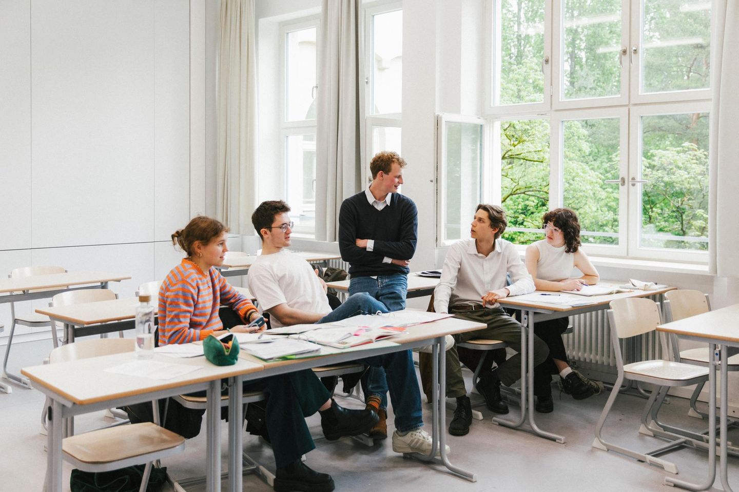 Fünf Schüler:innen sitzen zusammen beim Lernen in einem Klassenzimmer