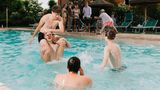 Vier junge Männer spielen im Wasser Wrestling