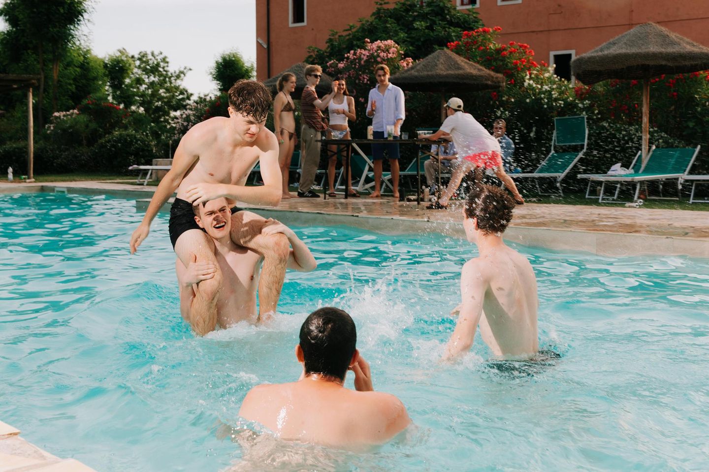 Vier junge Männer spielen im Wasser Wrestling