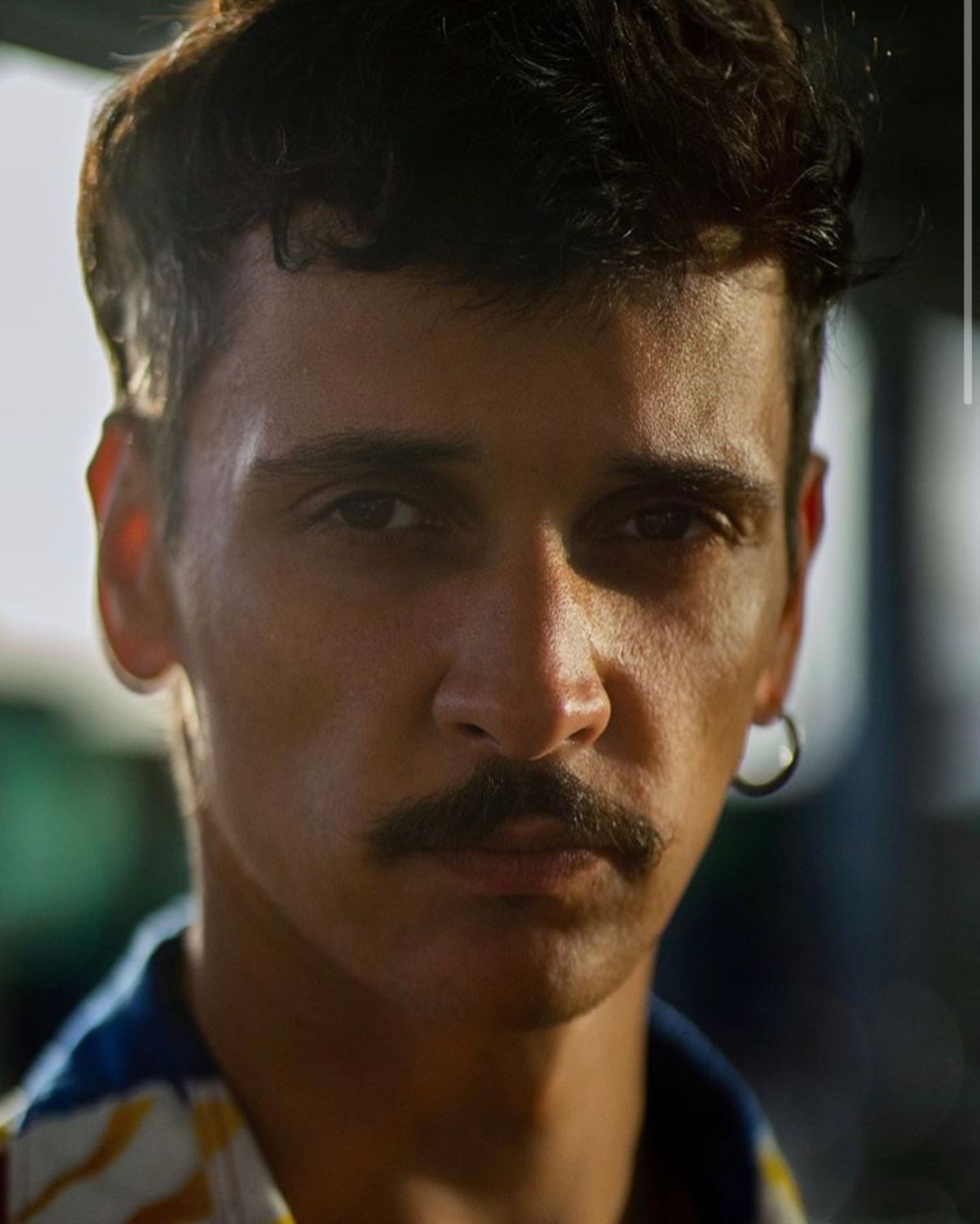 Schwulsein in Berlin: Augusto Andrade, ein Mann mit Bart, schaut mit ernstem Blick in die Kamera