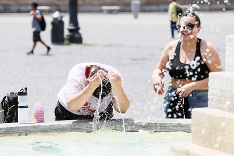Zwei Personen kühlen sich an einem Brunnen auf der Piazza del Popolo in Rom ab