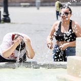 Zwei Personen kühlen sich an einem Brunnen auf der Piazza del Popolo in Rom ab