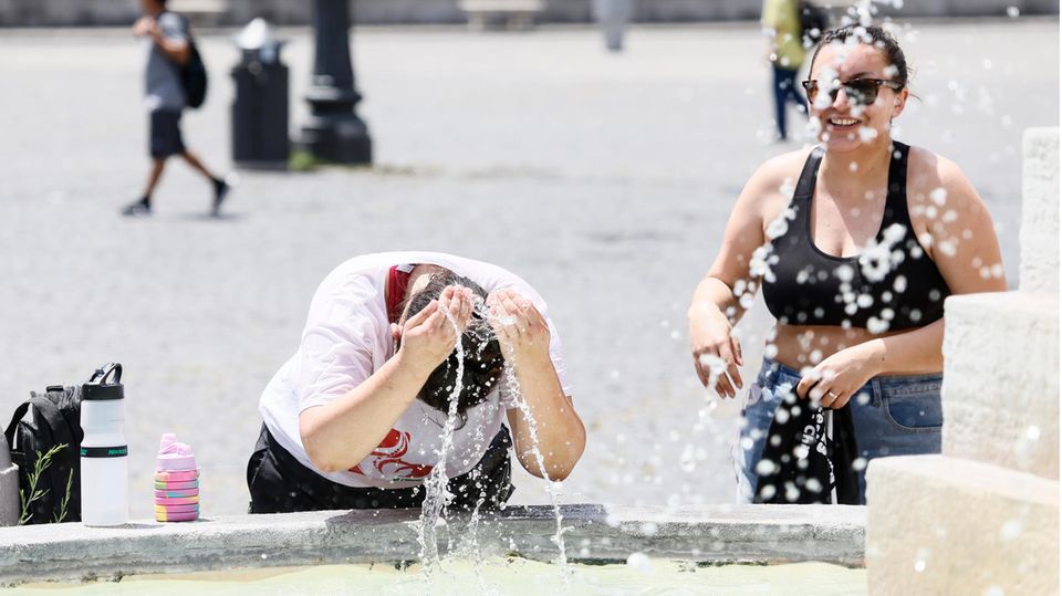 Zwei Personen kühlen sich an einem Brunnen auf der Piazza del Popolo in Rom ab