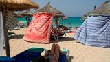 Unter Sonnenschirmen aus Stroh suchen Strandbesucher auf Mallorca Schutz vor der brennenden Sonne