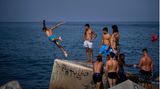 Ein bisschen Show muss sein: Am Strand von Barcelona springt dieser junge Mann von einem Wellenbrecher ins Mittelmeer