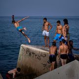 Ein bisschen Show muss sein: Am Strand von Barcelona springt dieser junge Mann von einem Wellenbrecher ins Mittelmeer