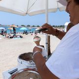 Ein Eisverkäufer steht am Strand eines Athener Vorortes und löffelt gerade eine Kugel Eis in ein Waffelhörnchen