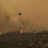 Ein Hubschrauber wirft über einem brennenden Wald in Griechenland Wasser aus