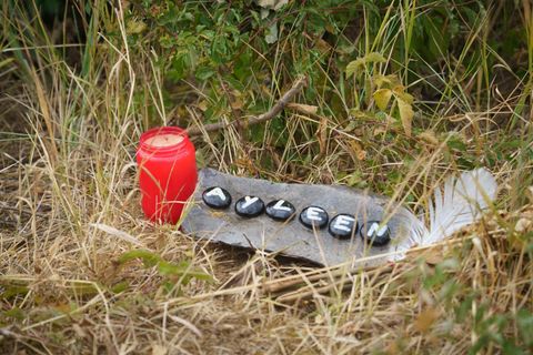 Neben einer Grabkerze liegt ein Stein mit aufgemaltem "Ayleen" im Gras