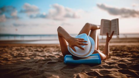 Person liest am Strand ein Buch