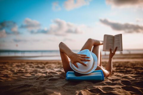 Person liest am Strand ein Buch