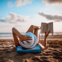Person liest am Strand ein Buch