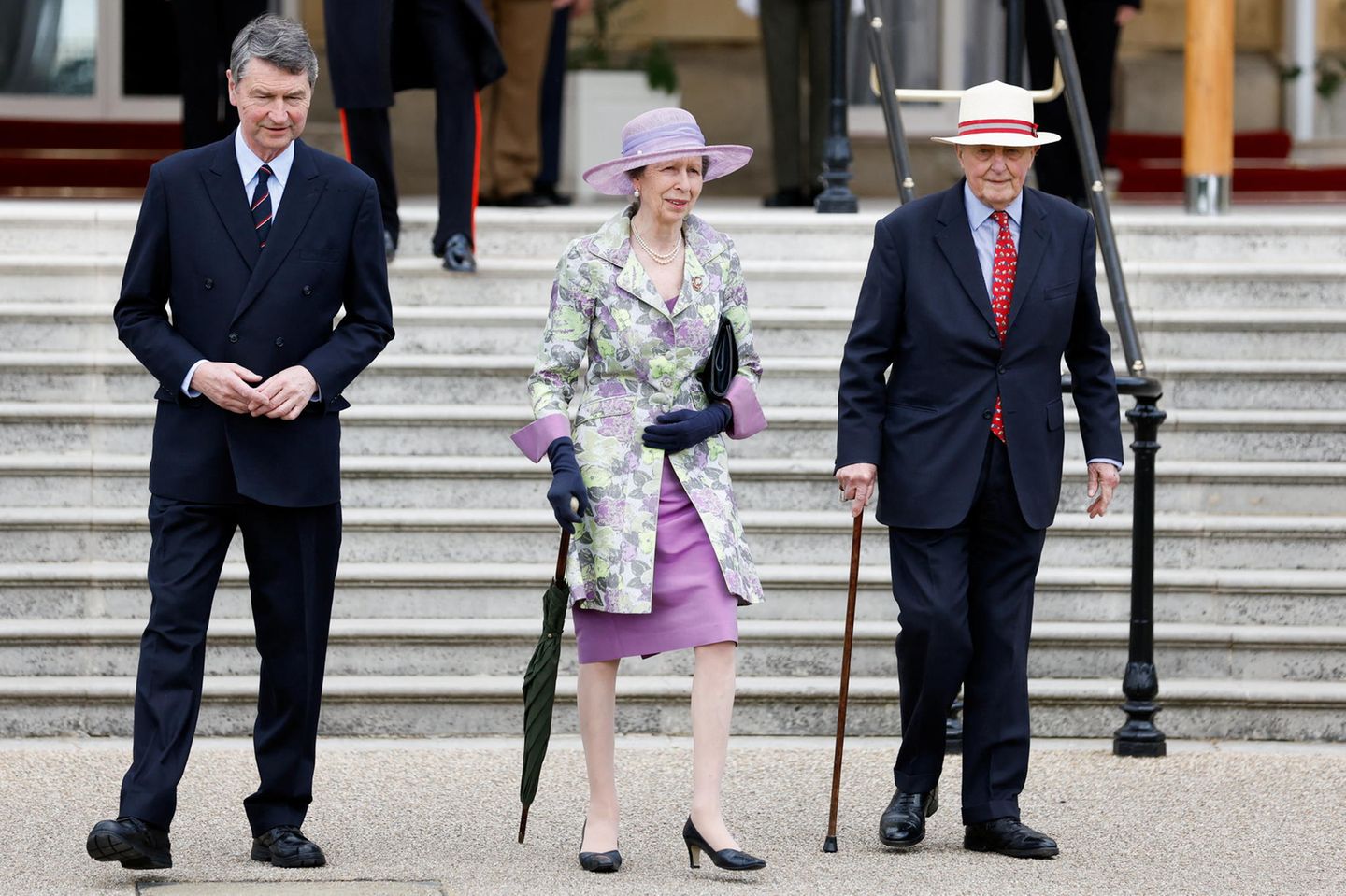 Zu einer der letzten Gartenpartys, die Queen Elizabeth II. im Frühsommer 2022 ausrichtet, erscheint Prinzessin Anne in Begleitung ihres Ehemanns Sir Timothy Laurence (l.). Sie trägt Handschuhe, andere Pumps und einen anderen Hut, aber der farbenfrohe Look ist derselbe wie bei der Cambridge-Hochzeit. Nur elf Jahre später