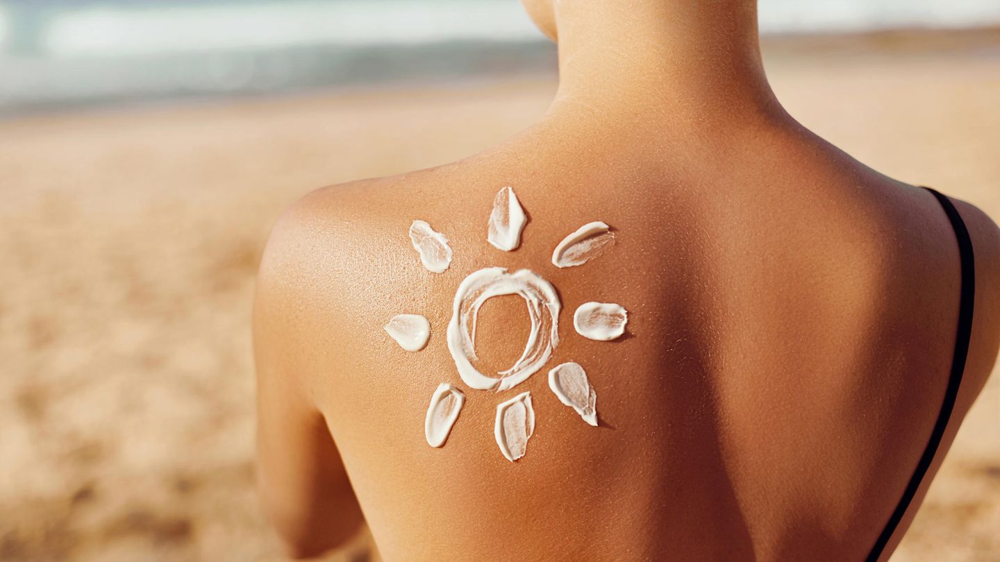 Auf dem Rücken einer Frau ist mit Creme eine Sonne aufgemalt.