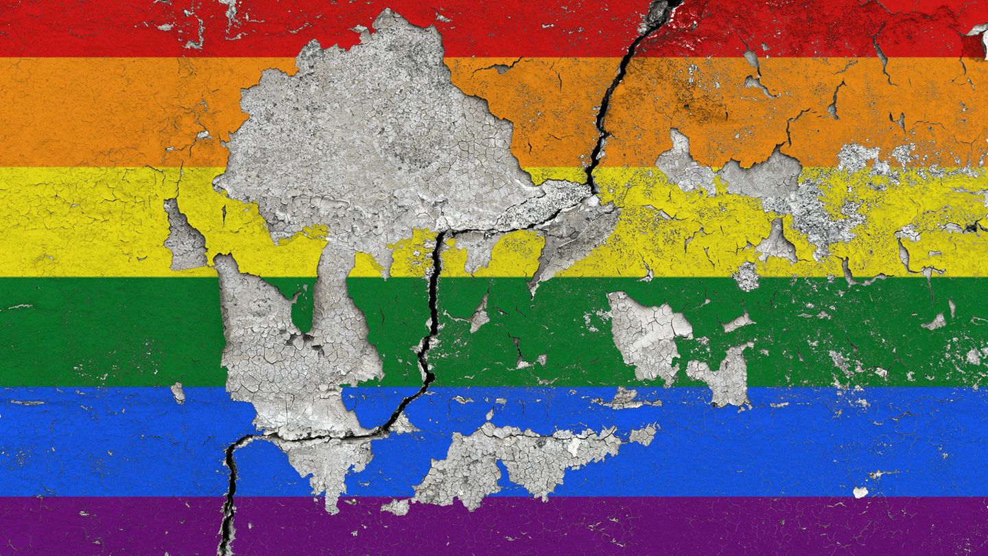 Eine Regenbogenfahne an einer Wand, von der der Putz abblättert