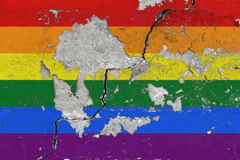Eine Regenbogenfahne an einer Wand, von der der Putz abblättert