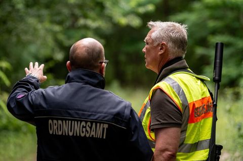 Der Gemeindejäger (r.) und ein Mitarbeiter Ordnungsamt durchsuchen im Bereich der südlichen Landesgrenze von Berlin den Wald