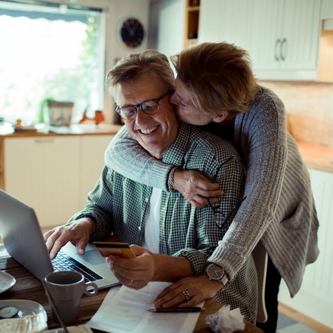 Eine Frau umarmt einen Mann von hinten und küsst ihn