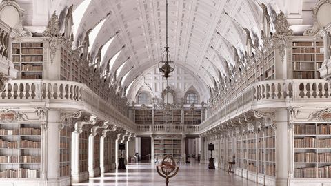 Die Palastbibliothek von Mafra gehört zu den prächtigsten Rokoko-Bibliotheken der Welt. 1771 wurde der vom königlichen Architekten Manuel Caetano de Sousa entworfene Saal fertiggestellt. Ursprünglich waren Vergoldungen und gemalte Dekorationen geplant. Daraus wurde jedoch nichts. Und so dominieren helle Farbtöne die Ausgestaltung des Prachtbaus, in dem 35.000 historischen Bände verwahrt werden. Um sie zu schützen, werden 500 Fledermäuse in der Bibliothek gehalten, die nachts alle Insekten, Fliegen und Larven beseitigen. 