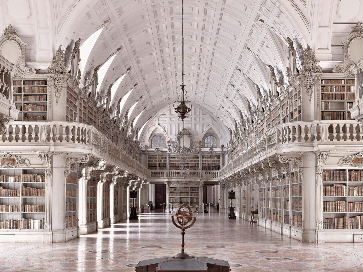 Die Palastbibliothek von Mafra gehört zu den prächtigsten Rokoko-Bibliotheken der Welt. 1771 wurde der vom königlichen Architekten Manuel Caetano de Sousa entworfene Saal fertiggestellt. Ursprünglich waren Vergoldungen und gemalte Dekorationen geplant. Daraus wurde jedoch nichts. Und so dominieren helle Farbtöne die Ausgestaltung des Prachtbaus, in dem 35.000 historischen Bände verwahrt werden. Um sie zu schützen, werden 500 Fledermäuse in der Bibliothek gehalten, die nachts alle Insekten, Fliegen und Larven beseitigen. 
