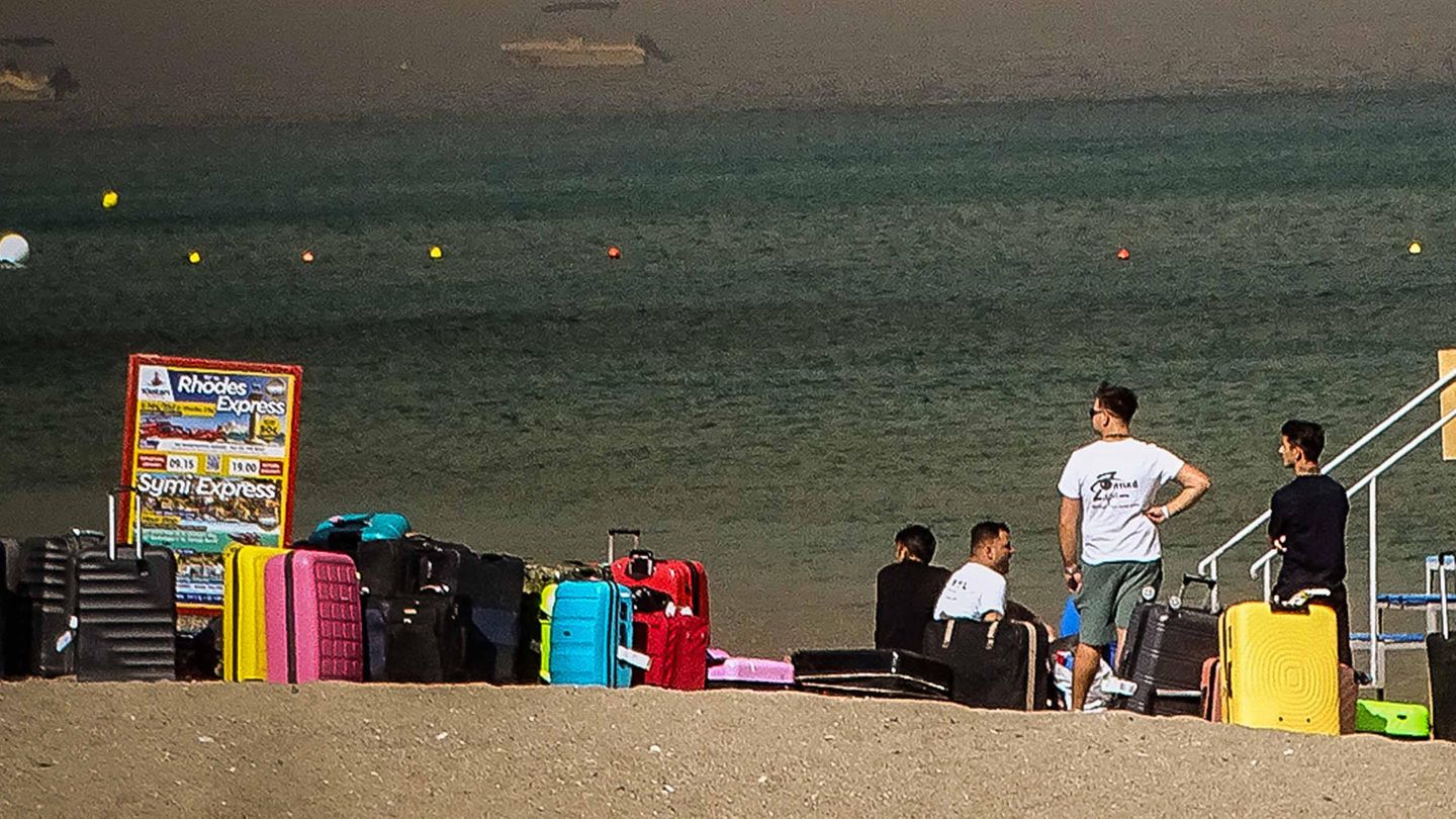Touristen warten am Strand von Rhodos darauf, vor den Waldbränden evakuiert zu werden