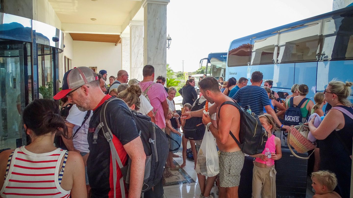 Touristen warten vor ihrem Hotel auf den Einstieg in Busse, um die Insel Rhodos wegen der schweren Waldbrände zu verlassen