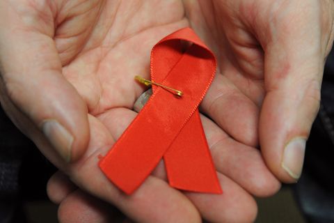 Ein mit dem HI-Virus infizierter Mann hält eine rote Schleife als Symbol der Solidarität mit HIV-Positiven und Aids-Kranken
