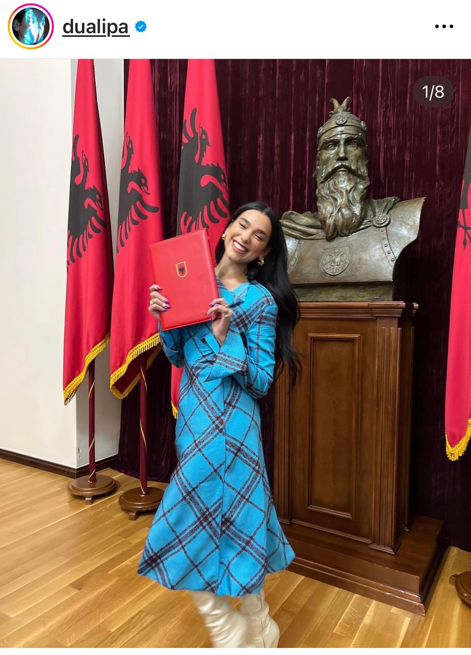 Dua Lipa holds up a red folder, in it her Albanian citizenship
