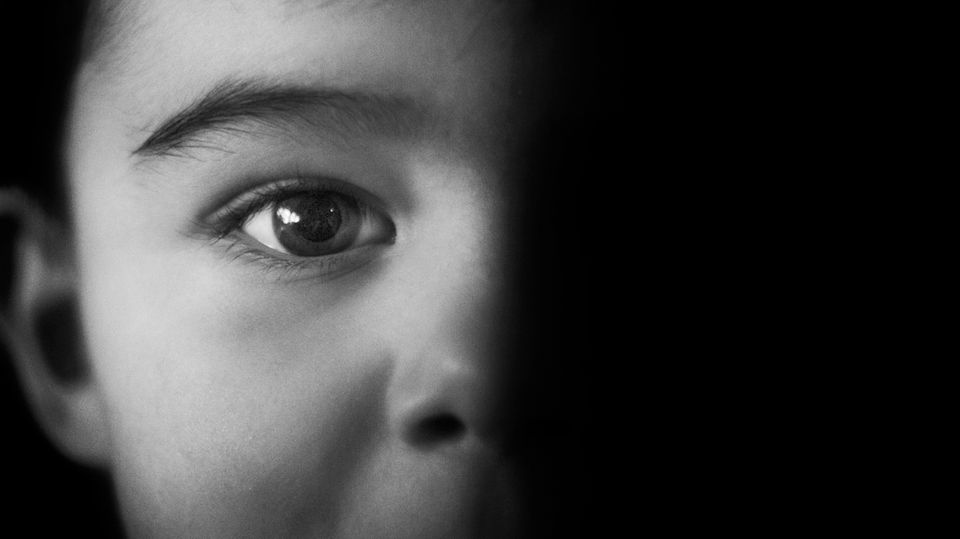 Schwarz-Weiß-Foto eines Kindes, von links angeleuchtet