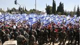 Israelische Sicherheitskräfte stehen Wache, während Demonstranten die Nationalflagge