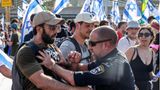 Ein Polizist schubst einen Demonstranten