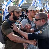 Ein Polizist schubst einen Demonstranten