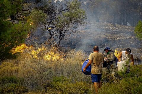Menschen mit Wasserkanistern kämpfen gegen die Flammen