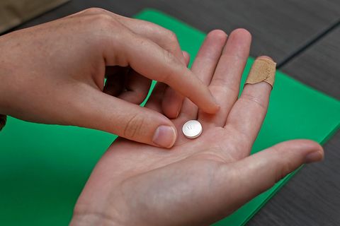 Eine weiße Abtreibungspille liegt auf der rechten Hand einer Frau, während die linke danach greift