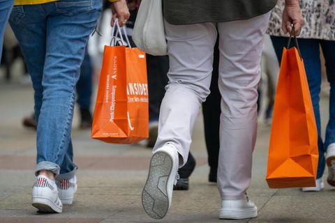 Menschen mit vollen Einkaufstaschen gehen an den Geschäften in der Tauentzienstraße in Berlin vorbei