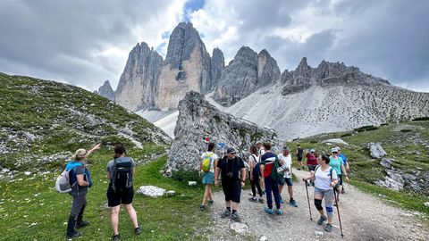 Wanderer in Südtirol passieren eine Gedenktafel für einen verunglückten Bergsteiger am Drei Zinnen Rundwanderweg