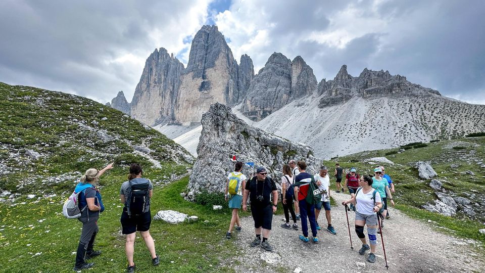 Wanderer in Südtirol passieren eine Gedenktafel für einen tödlich verunglückten Bergsteiger auf dem Drei Zinnen Rundwanderweg