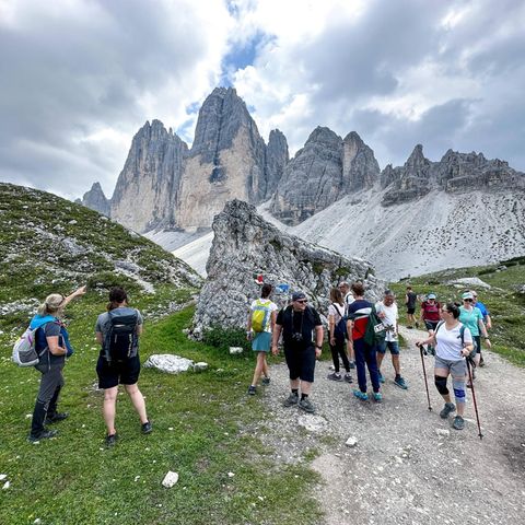 Wanderer in Südtirol passieren eine Gedenktafel für einen verunglückten Bergsteiger am Drei Zinnen Rundwanderweg