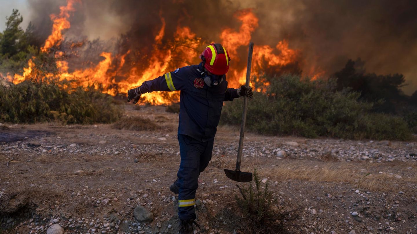 Ein Feuerwehrmann entfernt sich von Flammen eines Feuers auf Rhodos